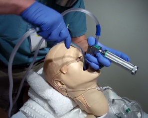 Portable suction pump (product code BTA) in use on a training manikin — details under NDA